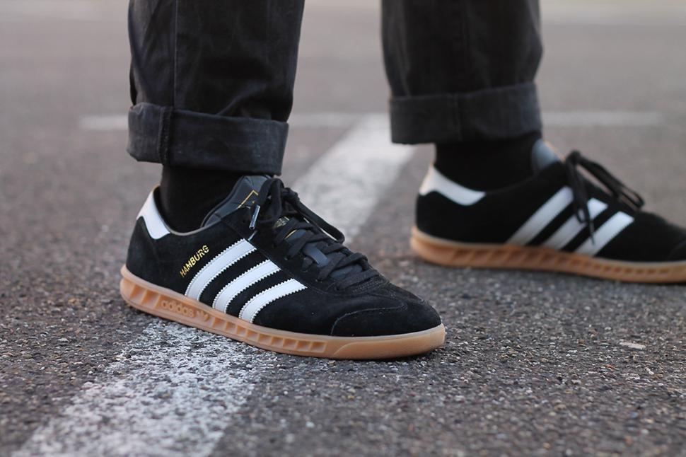 Free Image of Close-up of a person wearing black Adidas sneakers on the street 