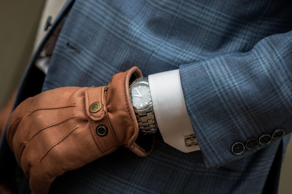 Free Image of Person in blue suit wearing gloves checking silver wristwatch 