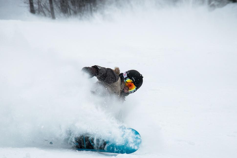Free Image of Action shot of a snowboarder carving through powder snow on slope. 