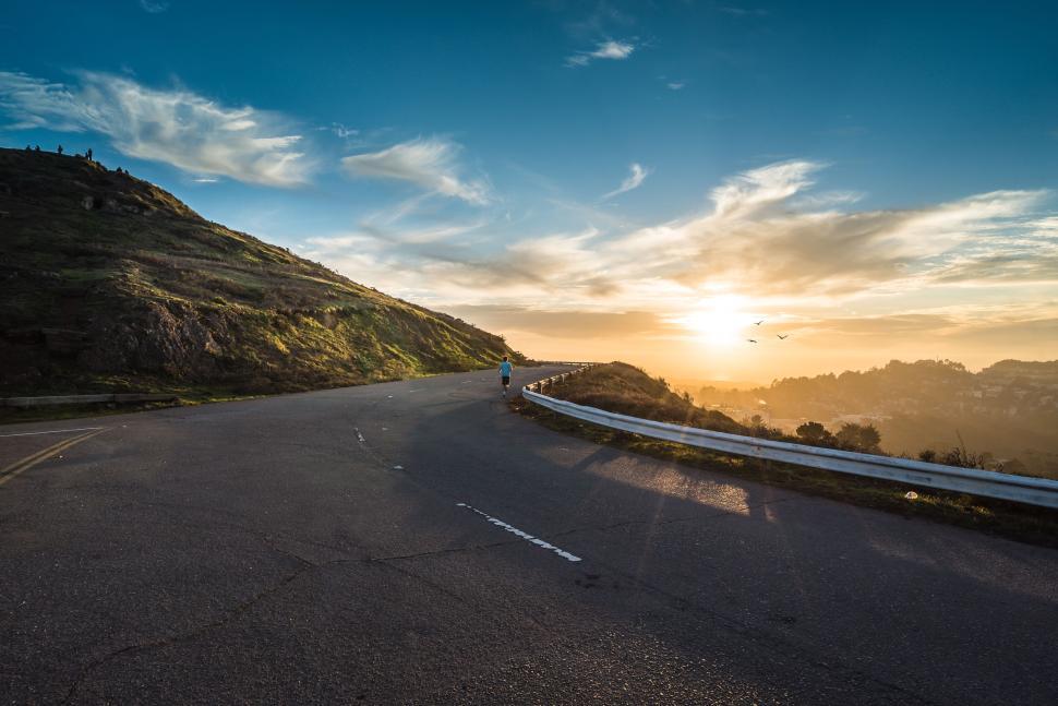 Free Image of Sunset over winding road with hilly landscape, rich blue sky views 