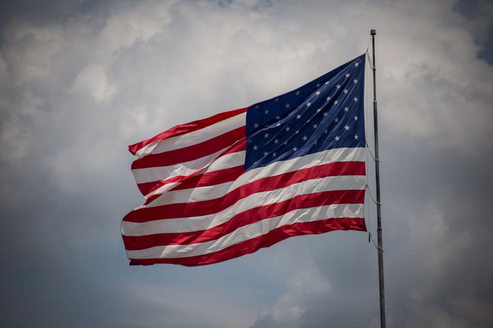 Free Image of American flag waving with cloudy sky backdrop symbolizing patriotism 