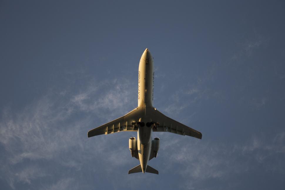 Free Image of Airplane viewed from below flying against clear blue sky backdrop 