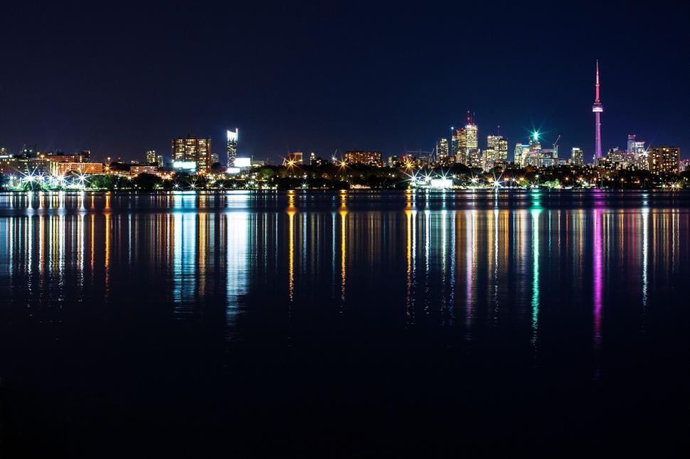 Free Image of Night city skyline reflected in calm waters with colorful lights 