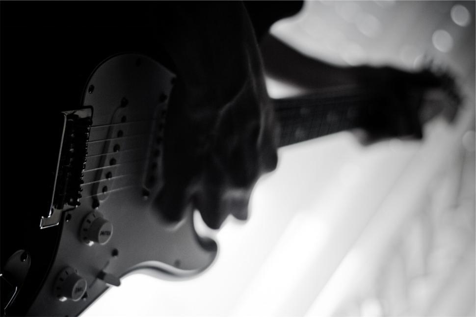 Free Image of Close-up of a person playing an electric guitar in monochrome lighting 