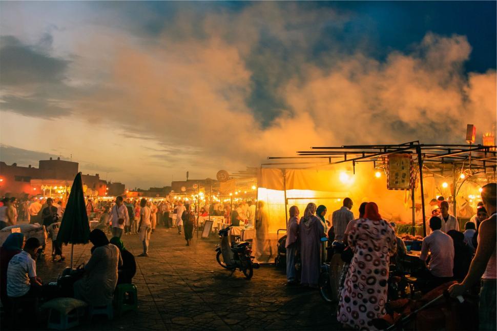 Free Image of Vibrant marketplace at dusk with people and food vendors, smoke rising 