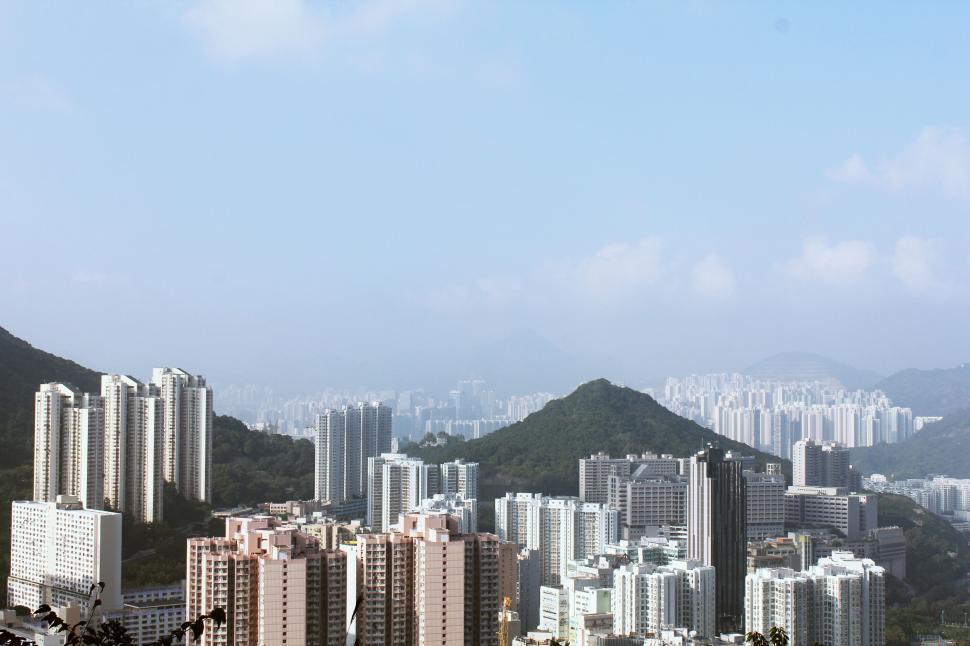 Free Image of Aerial view of cityscape with hills and high-rise buildings in fog. 
