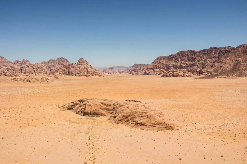 Free Image of Expansive desert landscape with distant mountain ranges under blue sky 