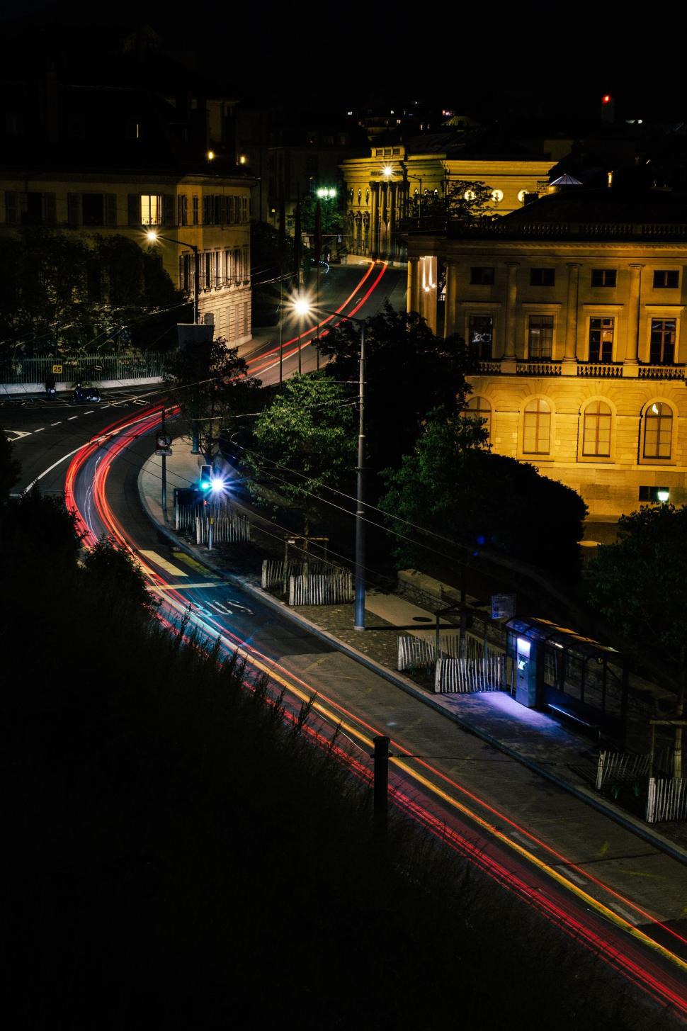 Free Image of City street at night with light trails and illuminated buildings view 