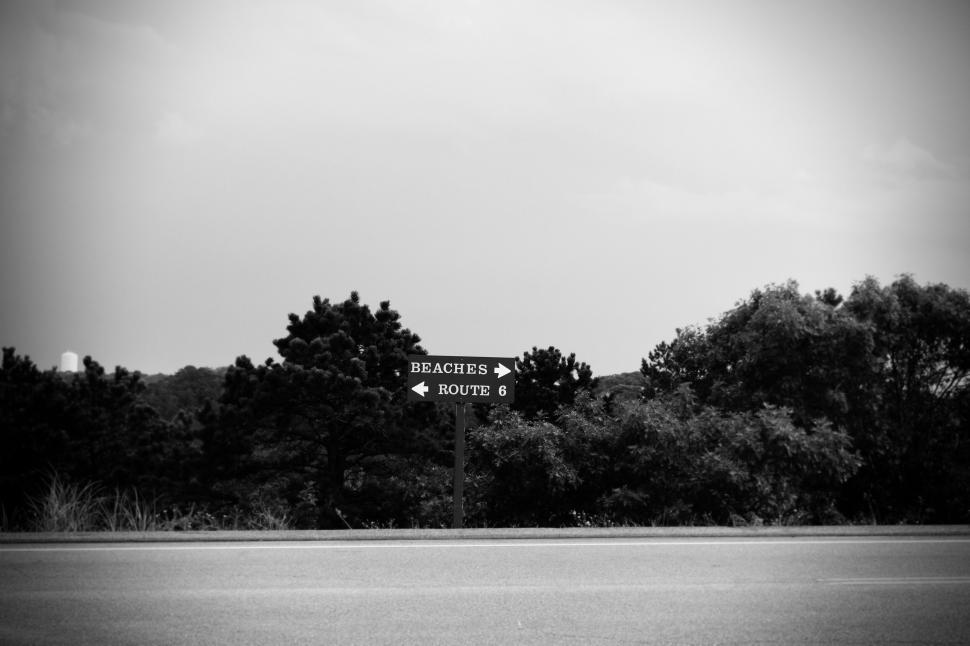 Free Image of A black-and-white signpost indicates directions to beaches and Route 6. 