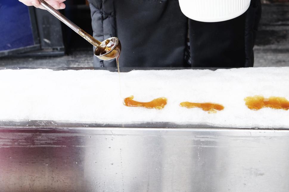 Free Image of Pouring syrup onto a line of snow for a sweet treat in the cold. 