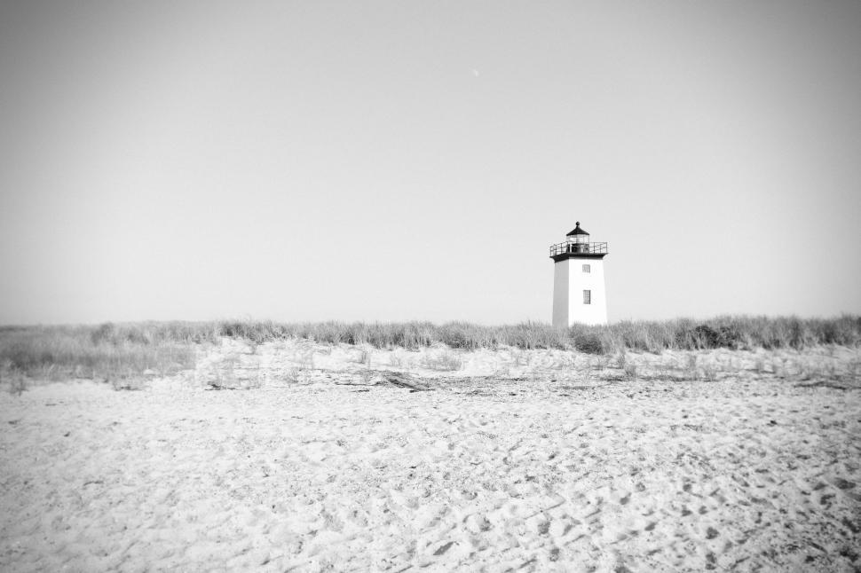 Free Image of A black and white photo of a lone lighthouse in a sandy landscape. 
