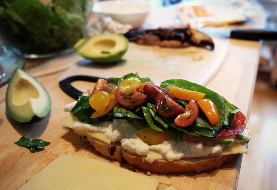 Free Image of Freshly made sandwich with avocado, tomatoes, and spinach on board 