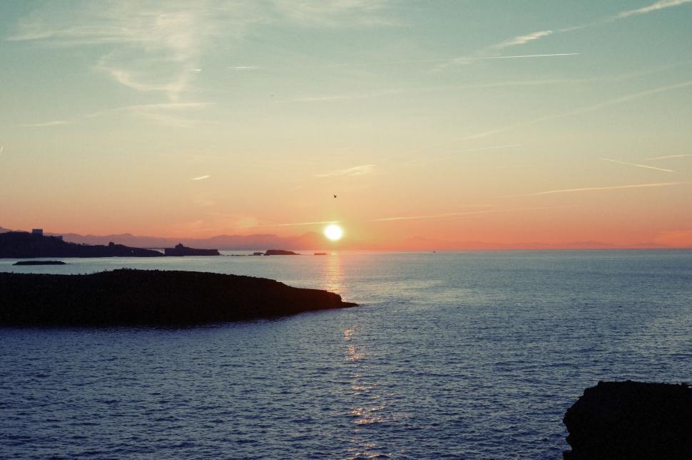 Free Image of Stunning ocean sunset with vibrant colors and calm waterfront view 