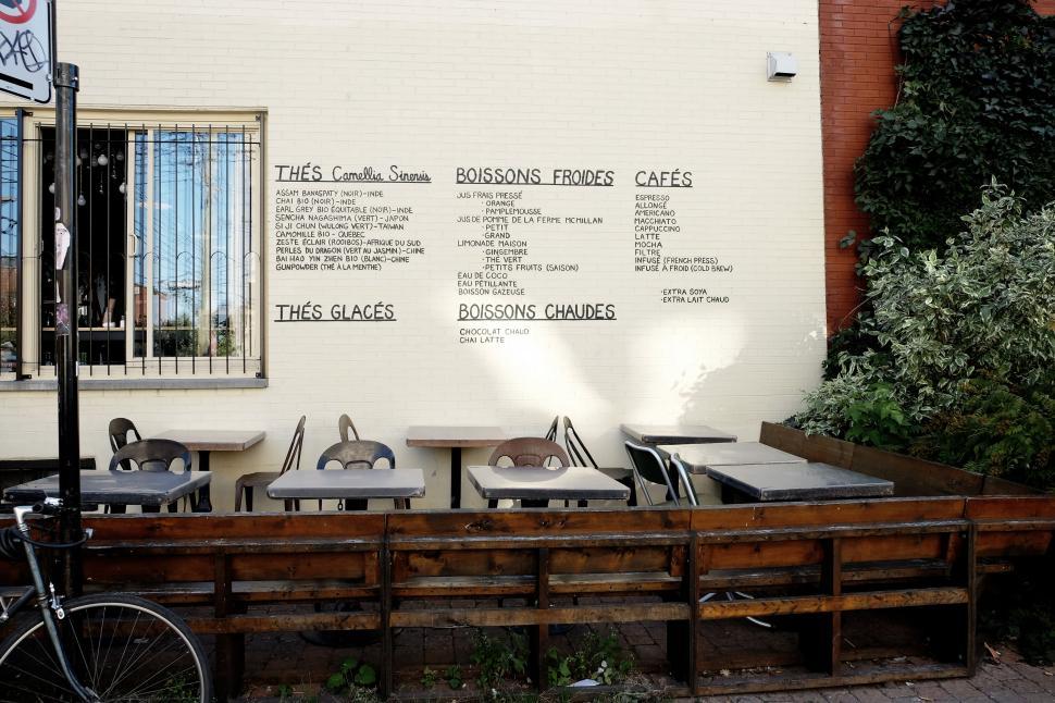 Free Image of Outdoor caf? area with menu on the wall, tables, and chairs. 