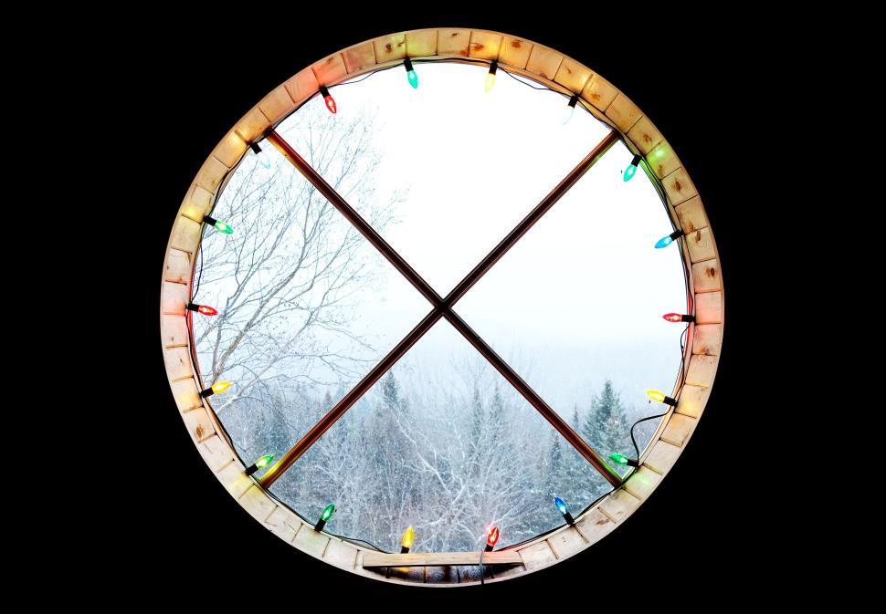 Free Image of Round window with colorful lights overlooking snowy winter scene. 