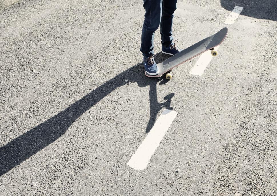 Free Image of Skateboarder balancing on the edge of a line in a parking lot 