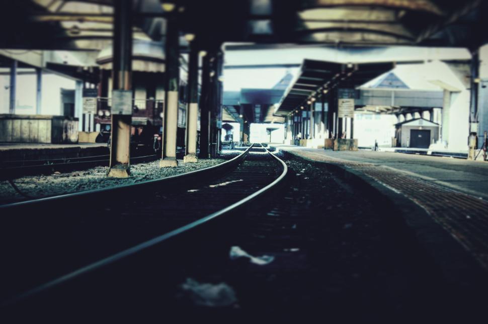 Free Image of Empty railway station platform with tracks leading into the distance 