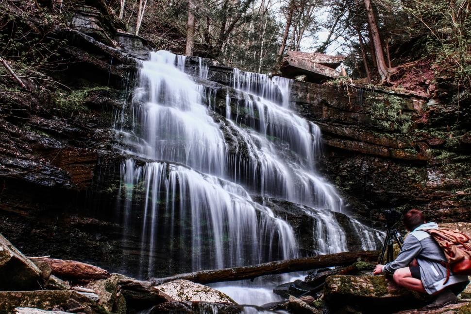 Free Image of Serene cascading waterfall surrounded by lush forest and rocks 