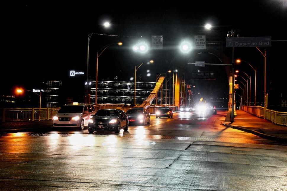 Free Image of Cars waiting on a well-lit city bridge at night with traffic signs. 