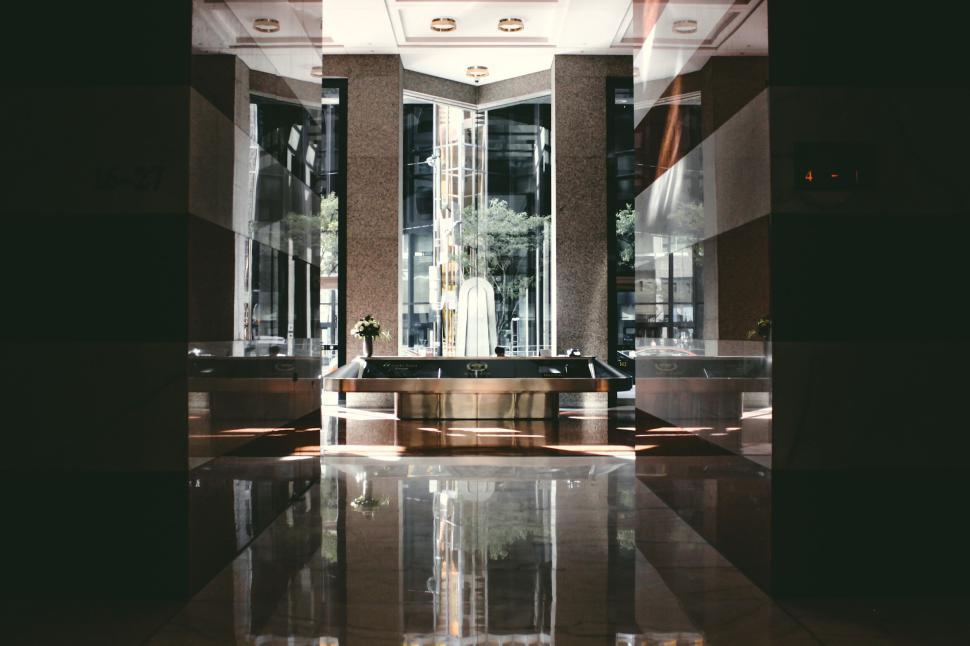 Free Image of Interior lobby with marble floors and reflective surfaces, daytime. 