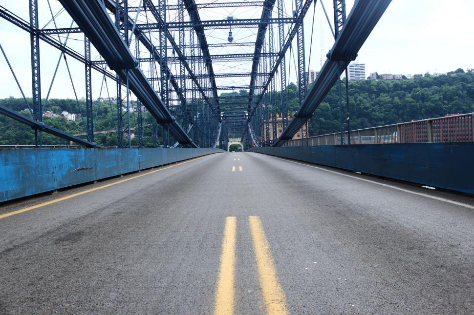 Free Image of Empty bridge with steel framework and clear road under blue sky. 