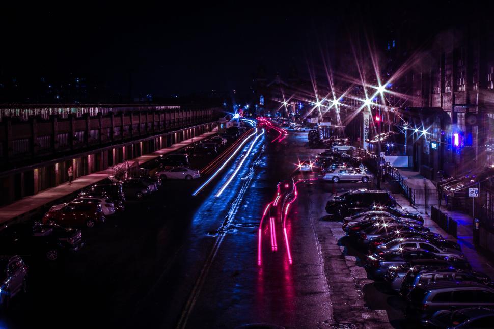 Free Image of Nighttime long exposure of street with car light trails and buildings. 