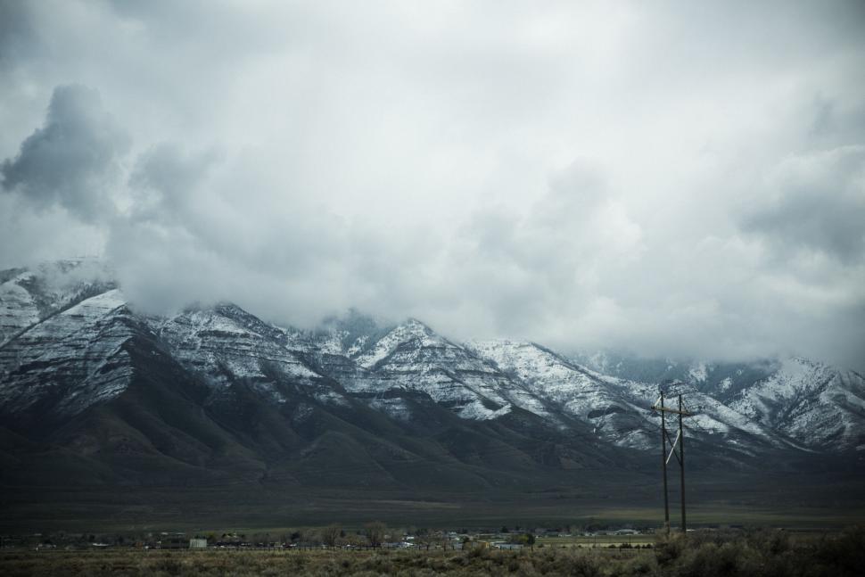 Free Image of Snow-capped mountain range under a cloudy sky blankets valley below. 
