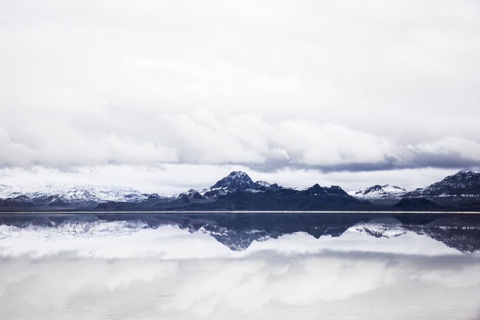 Free Image of Snow-covered mountain range reflected in still, icy lake. 