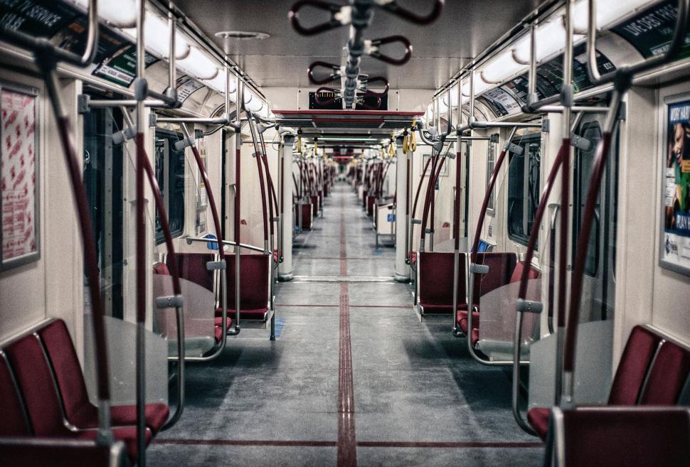 Free Image of Empty subway car with red seats and metal poles at night time. 
