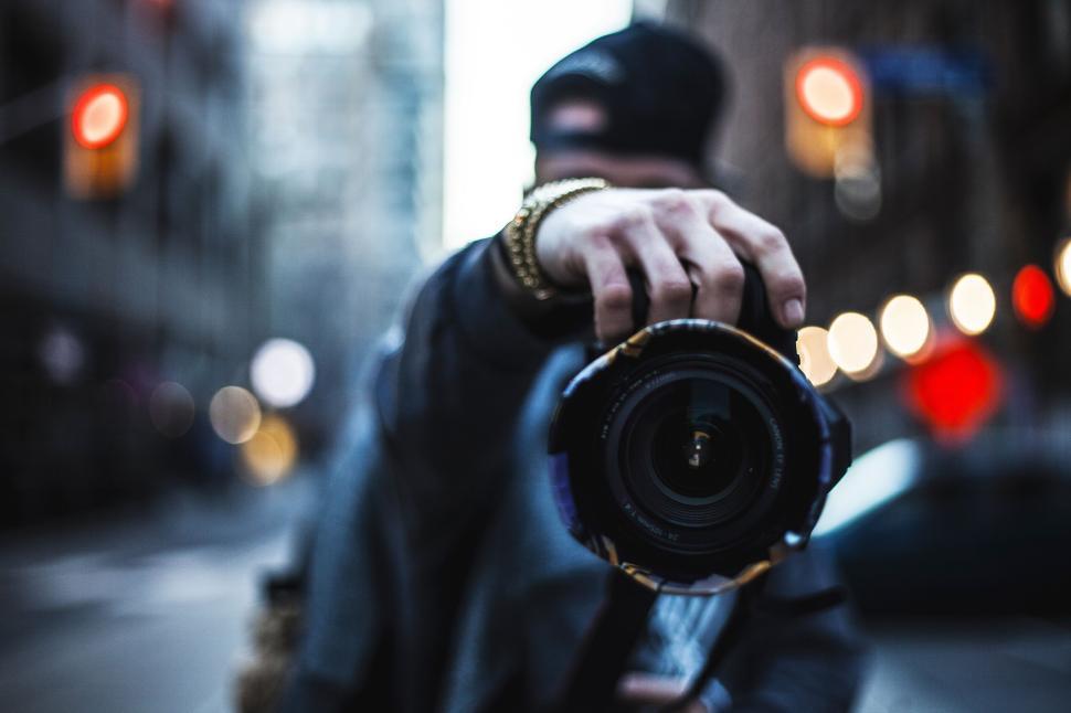 Free Image of Person holding up a camera lens towards the viewer on the street. 