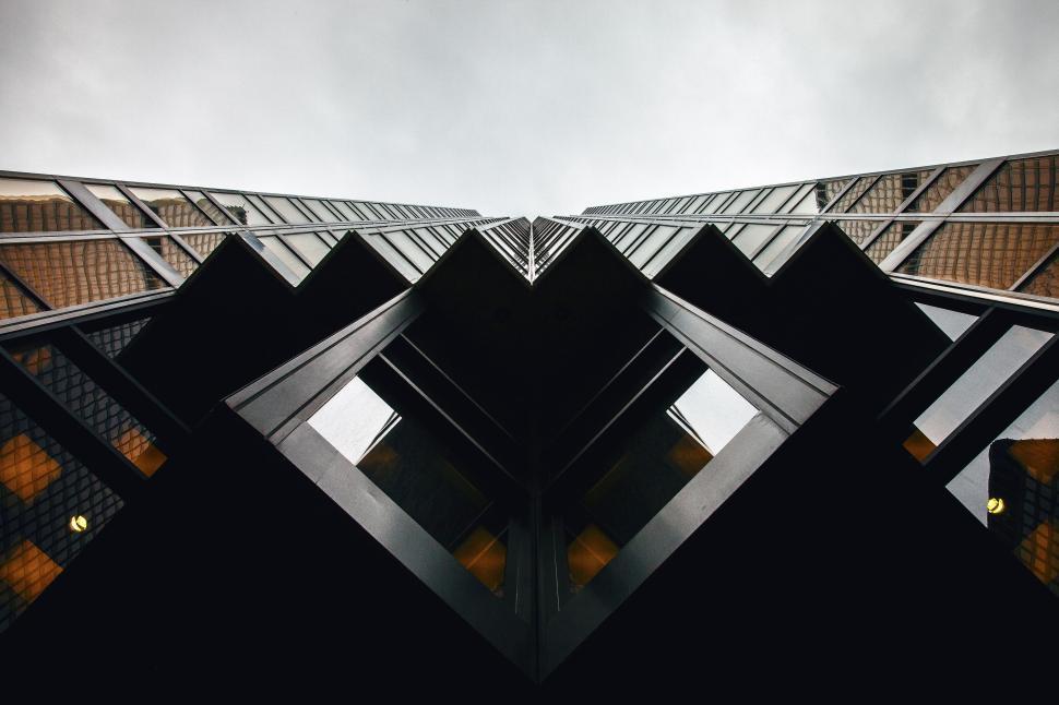 Free Image of Symmetrical view looking up at glass and steel high-rise buildings. 