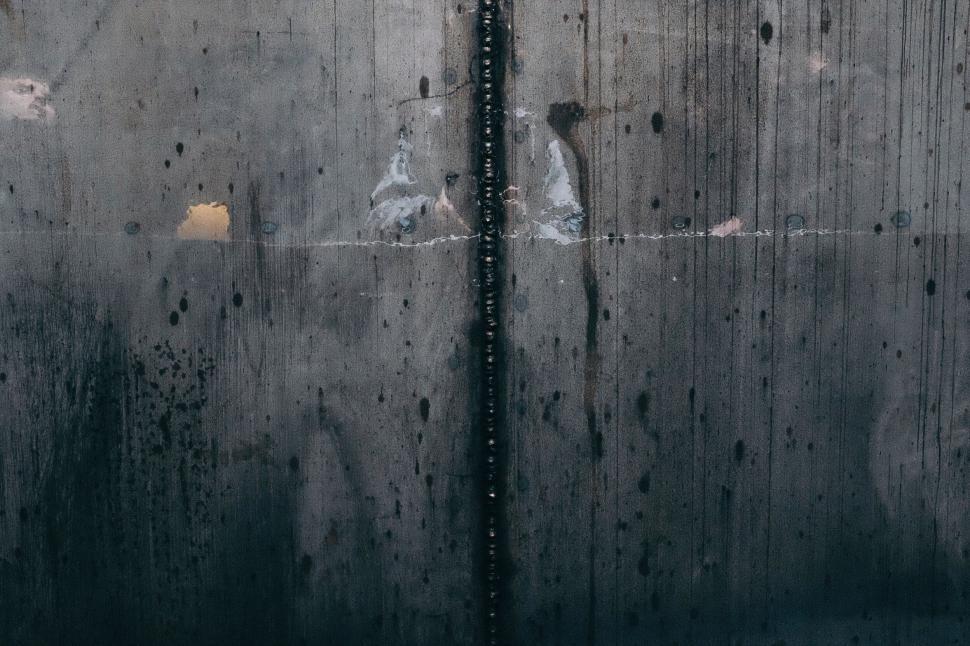 Free Image of Close-up view of a weathered concrete wall with vertical lines. 