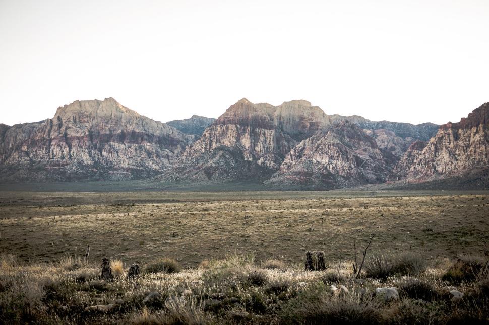 Free Image of Vast open desert plain leading to rugged mountain range at dawn 