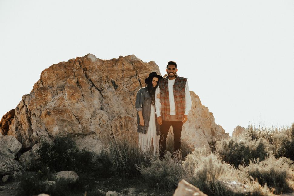 Free Image of Couple standing near a rocky outcrop in a natural landscape 