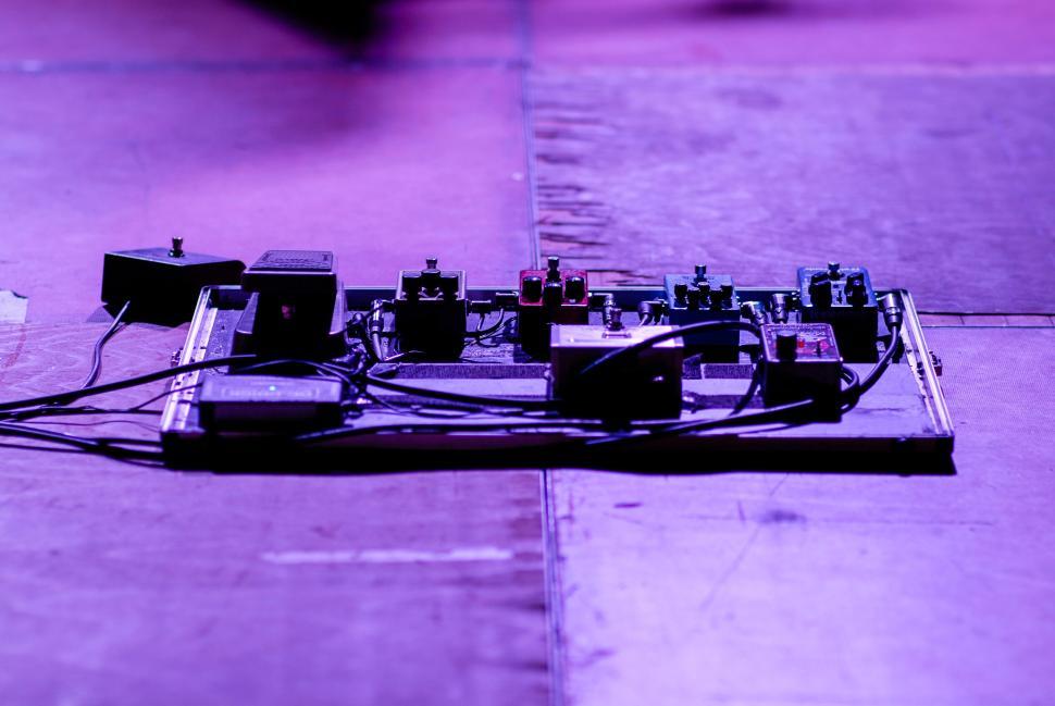 Free Image of Guitar pedalboard with multiple guitar effects pedals on stage. 