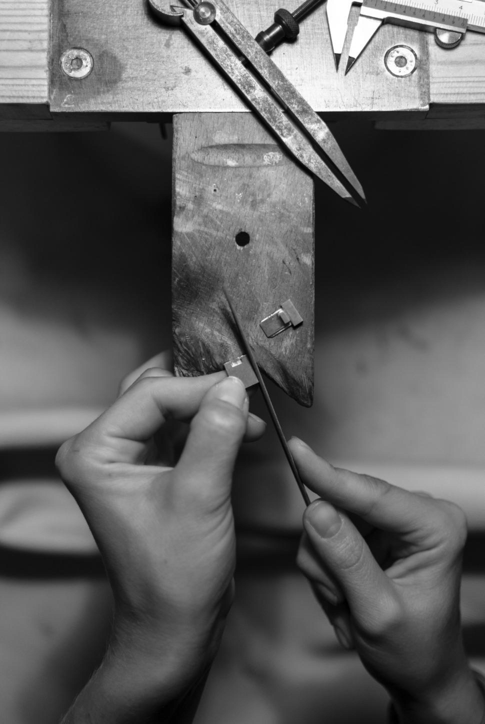 Free Image of Close-up of hands crafting jewelry on a workbench with tools. 