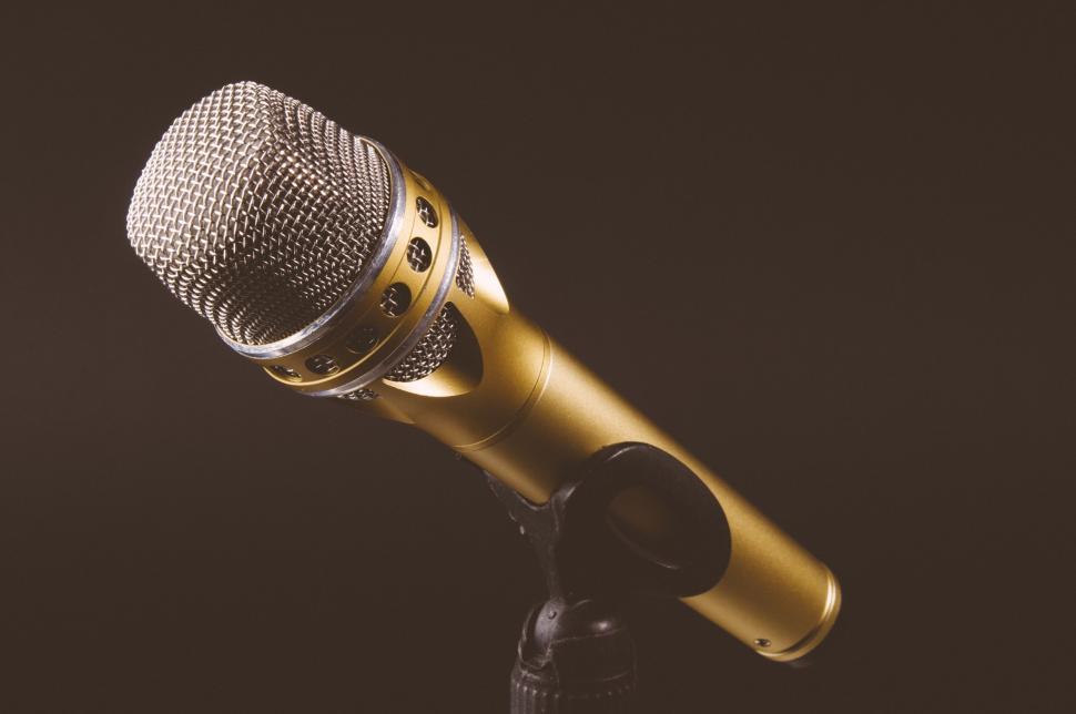 Free Image of Golden microphone on stand with a dark background and soft glow. 