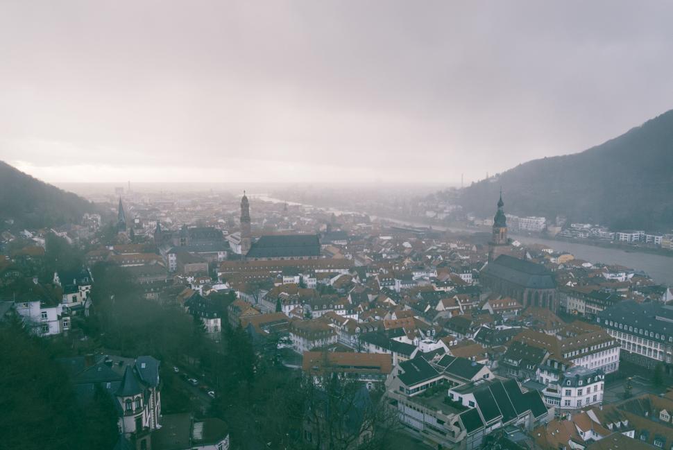Free Image of City aerial view on foggy morning with river and hills in distance 