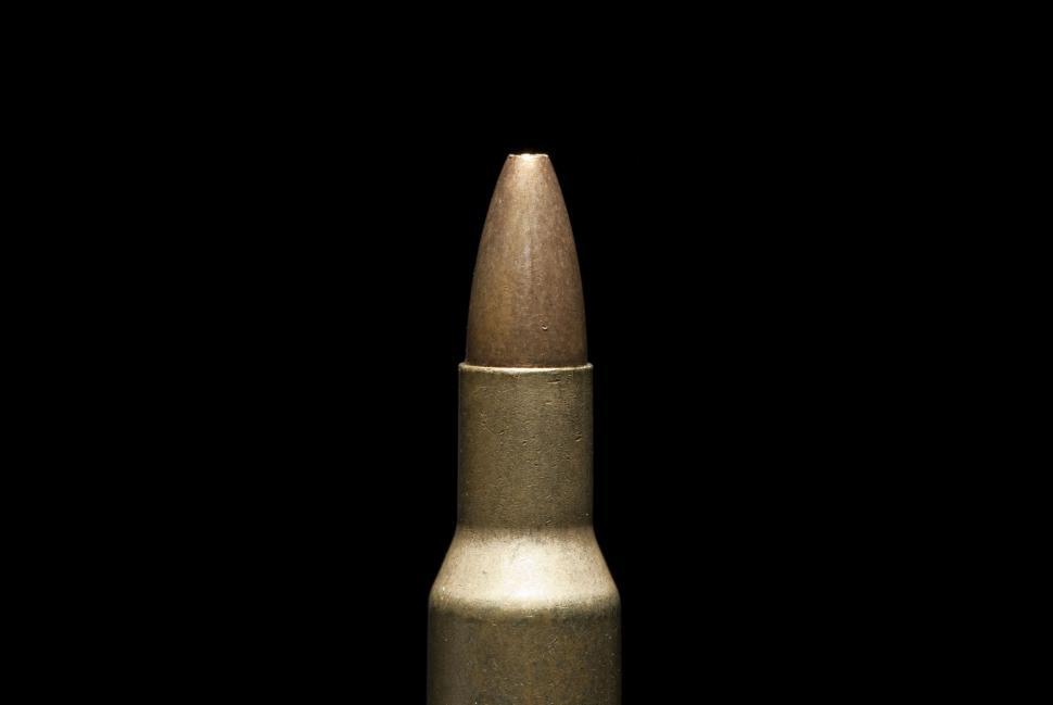Free Image of Close-up of single bullet with brass casing on solid black background 