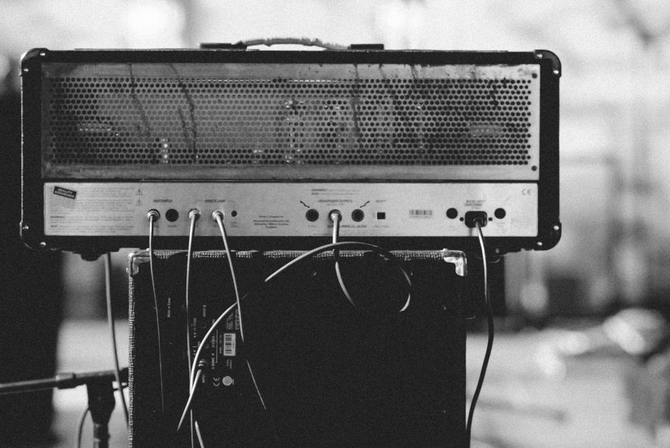 Free Image of Vintage guitar amplifier with cables plugged, monochrome image. 