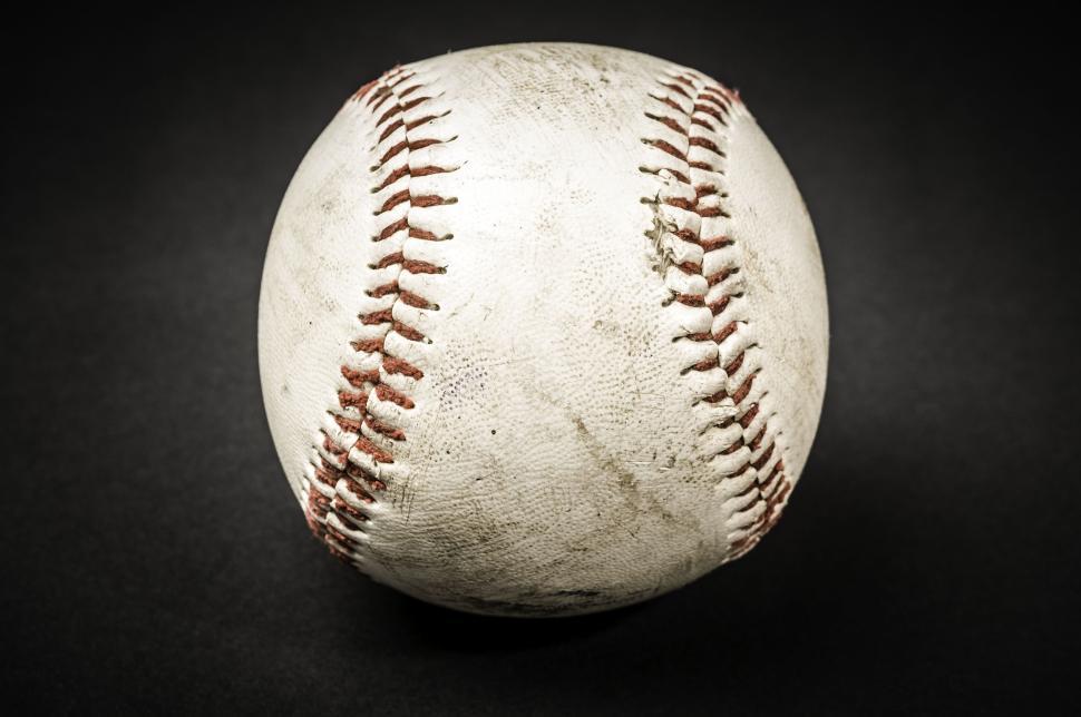 Free Image of Close-up image of a worn and dirty baseball on dark background. 