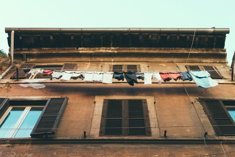 Free Image of Clothes hanging from the wires of a vintage building exterior 