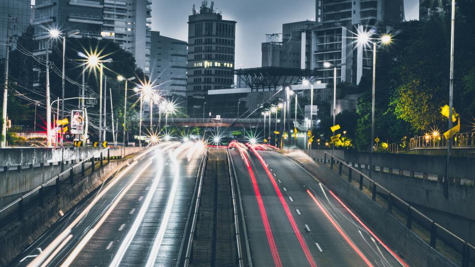 Free Image of City traffic at night with illuminated buildings in the background 