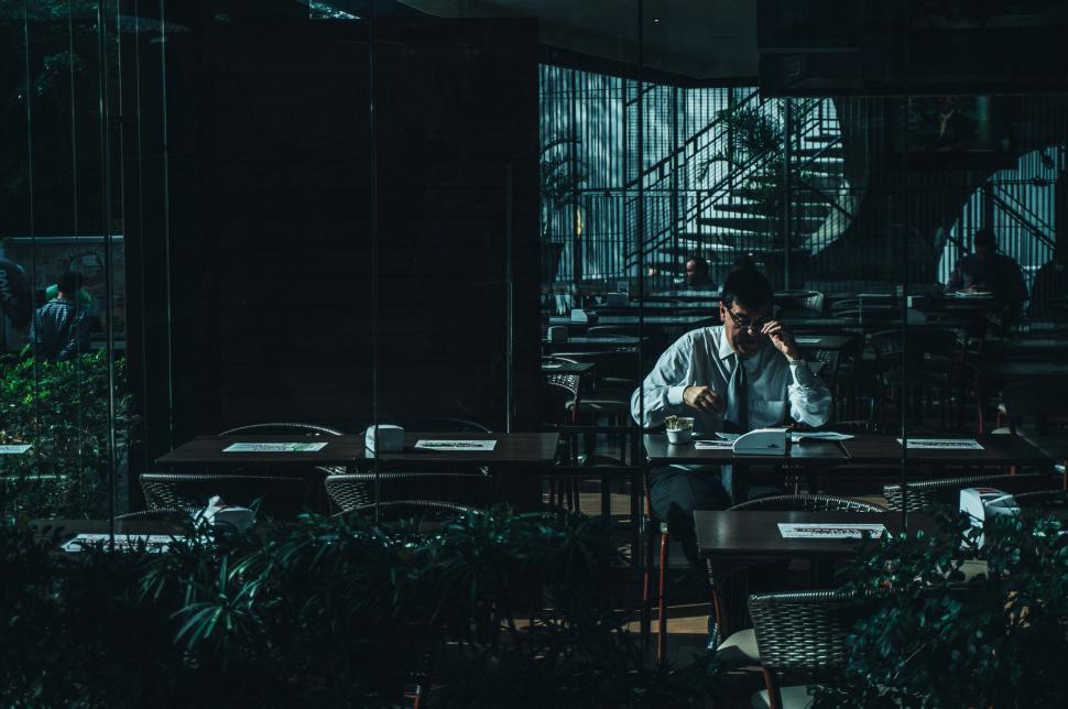 Free Image of Man in a dimly lit cafe sitting alone at a table with coffee. 