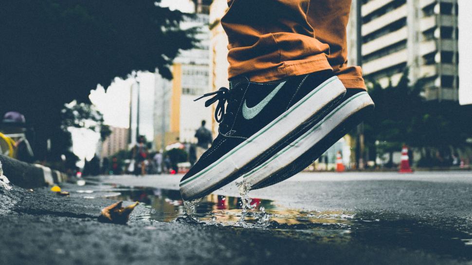 Free Image of Close-up of a person’s foot stepping into a puddle on an urban street. 