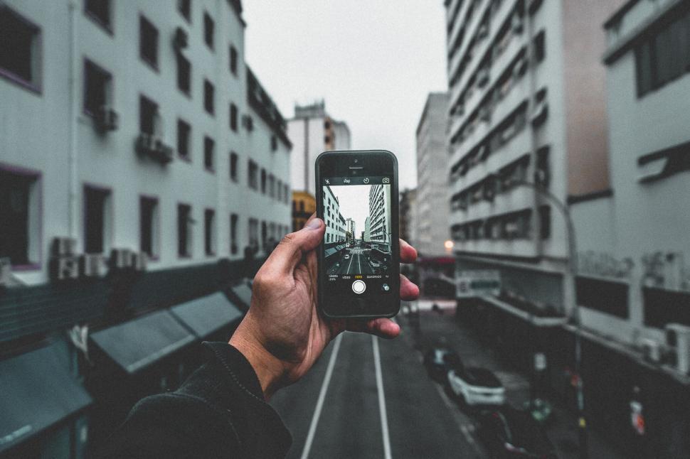 Free Image of Hand holding smartphone capturing view of urban street scene. 