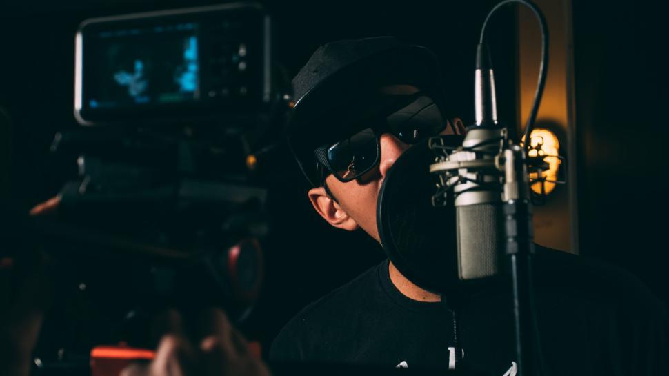 Free Image of Recording artist in a dark studio singing into a mic setup. 