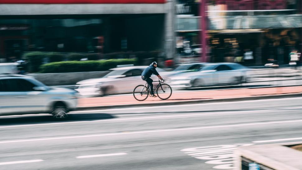 Free Image of Cyclist on Busy Urban Road with Blurred Cars in Motion at Day 