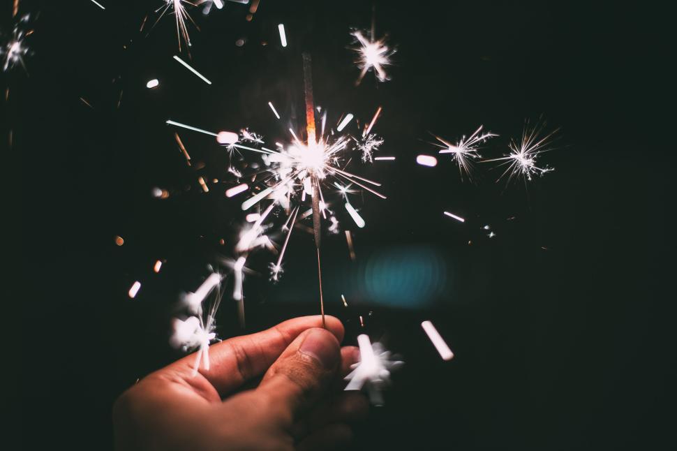 Free Image of Hand holding a bright sparkler in the dark with glowing sparks 