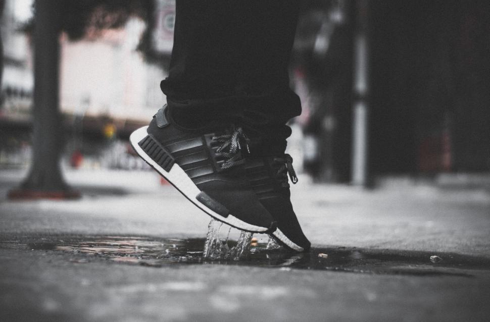 Free Image of Jumping feet in stylish black sneakers splashing water on street 